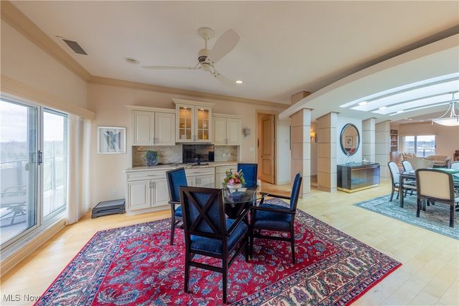 Dining area off kitchen with sliders to balcony. with light wood floors, recessed lighting, ceiling fan, crown molding. and built-ins | Image 6