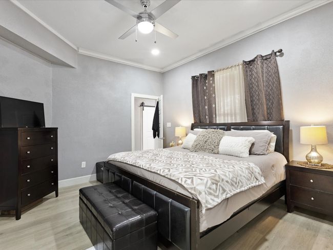 Bedroom with light wood-type flooring, ornamental molding, baseboards, and a ceiling fan | Image 10