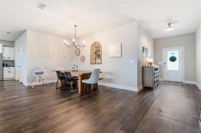 Dining area with dark hardwood / wood-style floors and a notable chandelier | Image 2