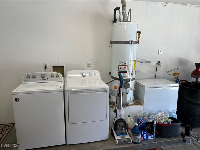 Laundry area with washer and clothes dryer and strapped water heater | Image 40
