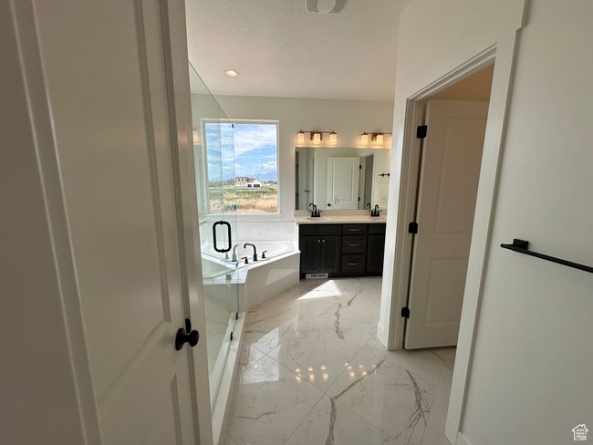 Full bathroom with double vanity, a garden tub, marble tiled floors, a textured ceiling, and a shower stall | Image 15
