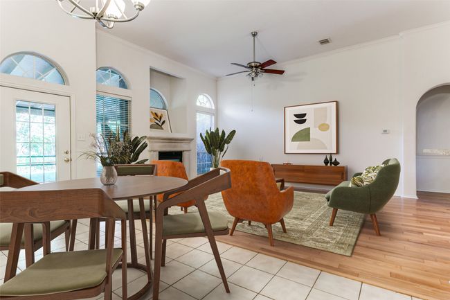 Dining space featuring ornamental molding, light wood-style flooring, a ceiling fan, a fireplace, and a chandelier | Image 14