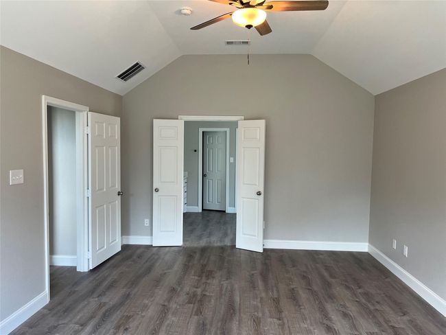 Unfurnished bedroom with lofted ceiling, dark wood finished floors, and ceiling fan | Image 18