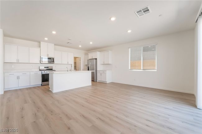 Kitchen featuring appliances with stainless steel finishes, open floor plan, light wood-style flooring, white cabinets, and recessed lighting | Image 7