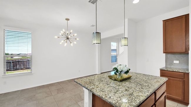 Kitchen with light stone counters, tasteful backsplash, plenty of natural light, and visible vents | Image 17