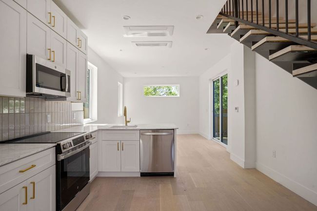 Kitchen with a peninsula, a sink, stainless steel appliances, light wood finished floors, and backsplash | Image 8