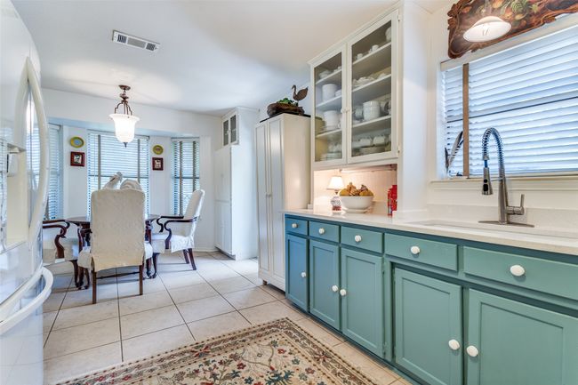 Kitchen with freestanding refrigerator, light tile patterned floors, light countertops, and hanging light fixtures | Image 15
