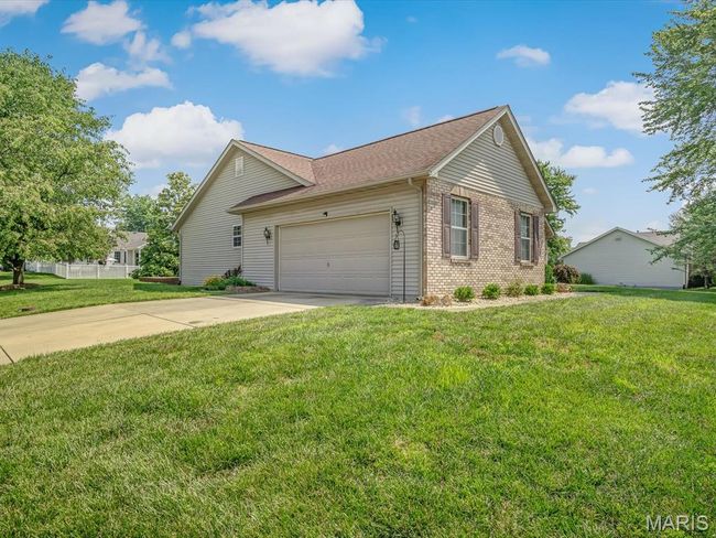 View of side of home with brick and vinyl siding, an attached garage, concrete driveway, and a lawn | Image 29