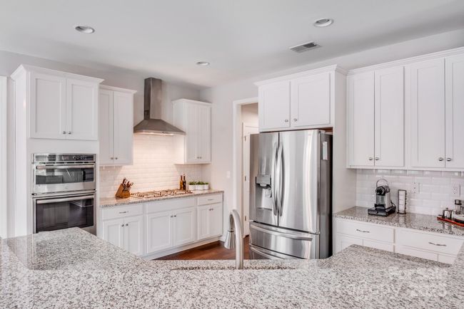 Gorgeous bright kitchen with granite countertops, white cabinets, stainless steel appliances and gas stove. | Image 18