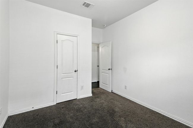 Unfurnished bedroom with dark colored carpet and baseboards | Image 17