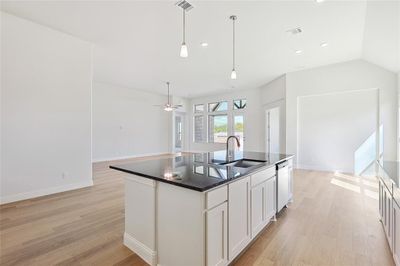 Kitchen with light hardwood / wood-style flooring, white cabinets, dishwasher, sink, and a center island with sink | Image 3