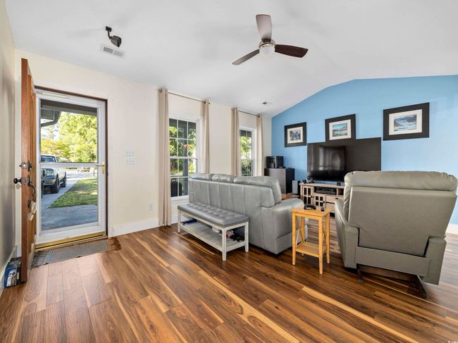 Living area with ceiling fan, visible vents, vaulted ceiling, dark wood finished floors, and baseboards | Image 4