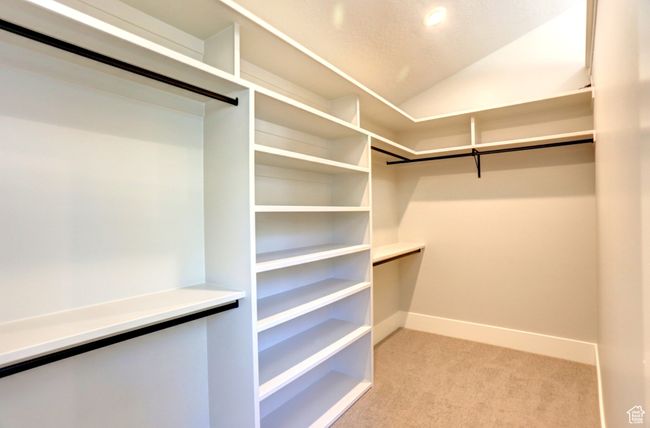 Walk in closet featuring light colored carpet and lofted ceiling | Image 27
