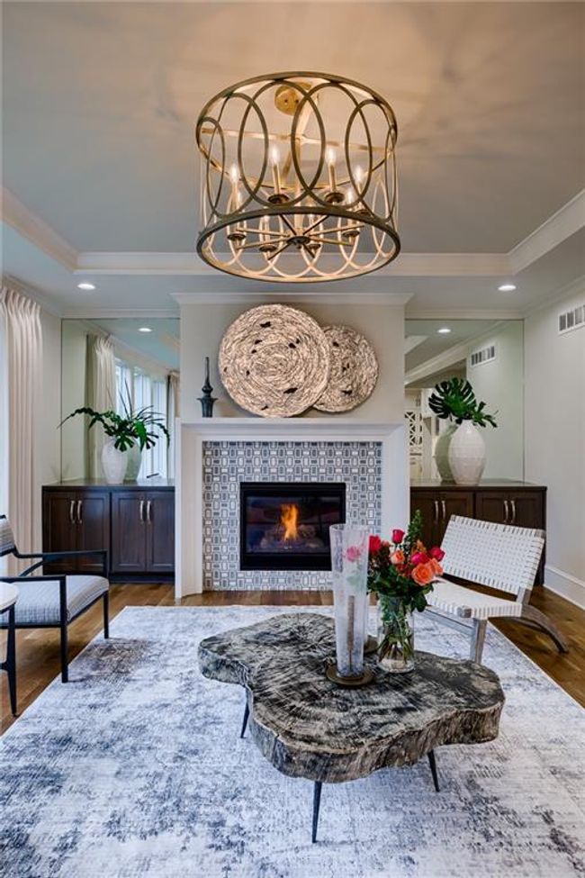Living room featuring a chandelier, crown molding, a tiled fireplace, and hardwood / wood-style floors | Image 7