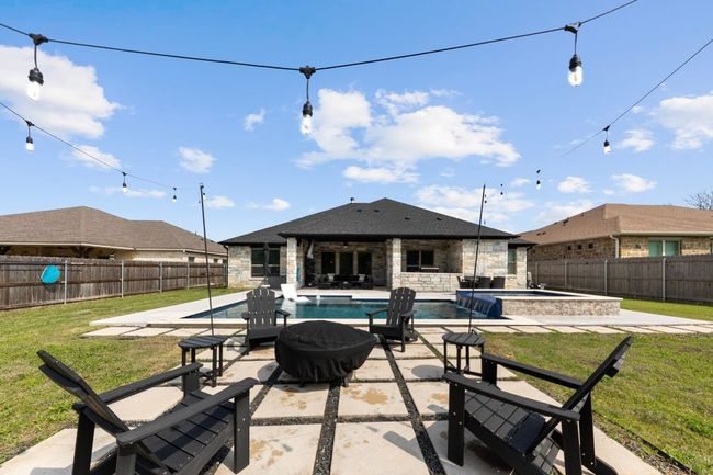 View of patio with an outbuilding, a fenced backyard, a pool with connected hot tub, and an exterior structure | Image 36