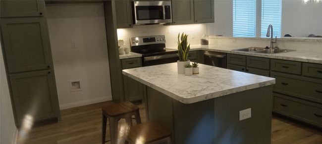 Kitchen featuring stainless steel appliances, dark wood finished floors, light countertops, and tasteful backsplash | Image 4