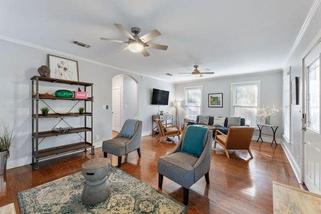 Living area with arched walkways, crown molding, ceiling fan, and wood finished floors | Image 4