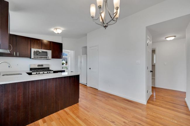 Kitchen with dark brown cabinetry, freestanding refrigerator, light wood-style flooring, baseboards, and visible vents | Image 8