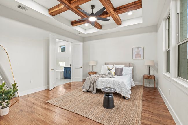 Bedroom with coffered ceiling, wood finished floors, beamed ceiling, connected bathroom, and multiple windows | Image 13