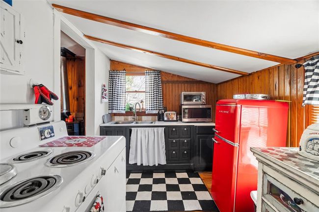 Kitchen featuring sink, wooden walls, electric range, and refrigerator | Image 10