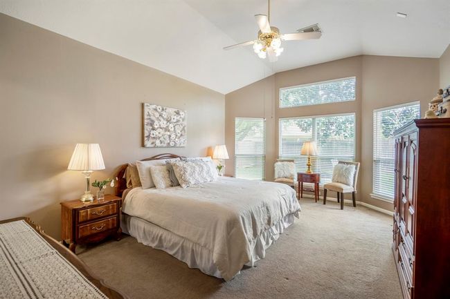 Entering the primary bedroom, you'll be greeted by charming bay windows with a transom window above, allowing for natural light and views of the outdoors. The vaulted ceilings enhance the spacious and airy feel of this private retreat. | Image 17