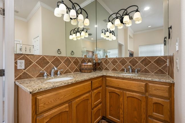 The primary bath shows off its tall double-sinked counters with great lighting and granite counters. | Image 12