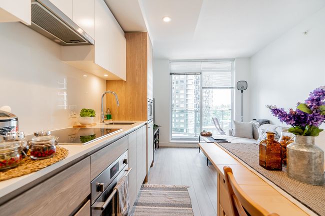 Kitchen with modern cabinets, under cabinet range hood, a sink, stainless steel appliances, and light countertops | Image 5