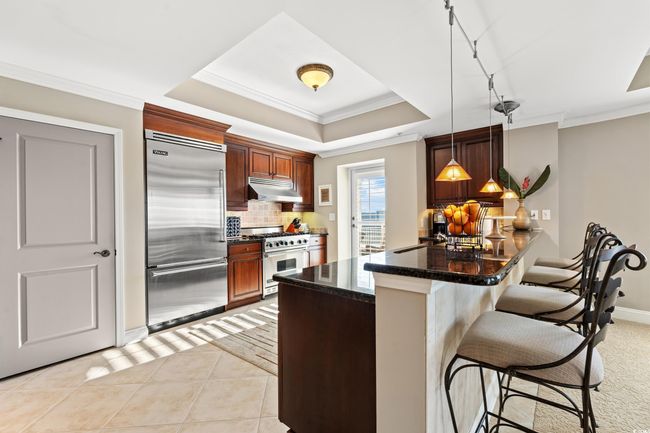 Kitchen featuring high end appliances, a kitchen bar, decorative backsplash, a peninsula, and pendant lighting | Image 18