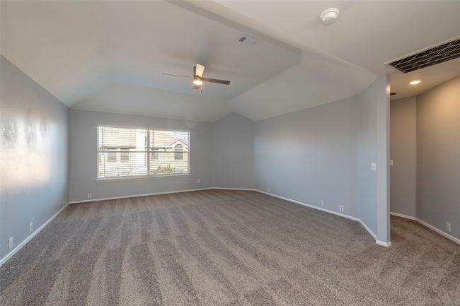 Carpeted empty room with vaulted ceiling, a ceiling fan, visible vents, and baseboards | Image 28