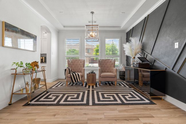 Living area featuring a raised ceiling, a chandelier, arched walkways, light wood-style flooring, and baseboards | Image 23