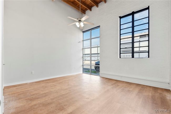 Empty room featuring high vaulted ceiling, wood finished floors, a wooden ceiling with exposed beams, ceiling fan, and brick wall | Image 11