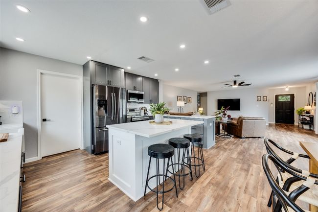 Kitchen with appliances with stainless steel finishes, a center island, a ceiling fan, gray cabinets, and light wood-style floors | Image 14