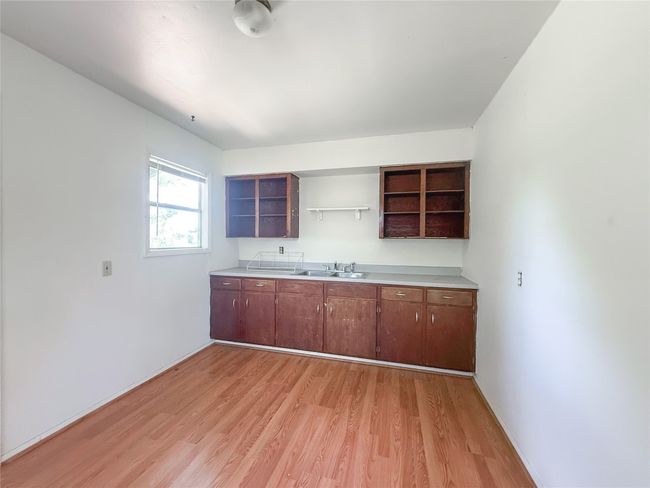 Kitchen with light wood-style floors, open shelves, and light countertops | Image 14