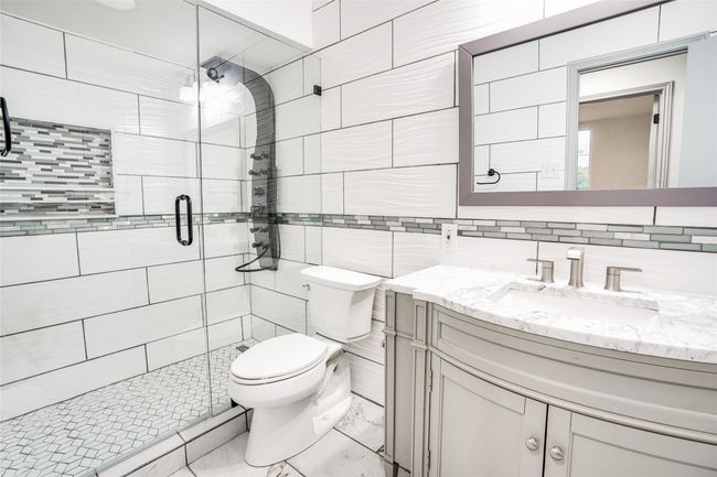 Bathroom with tile walls, vanity, toilet, a shower stall, and backsplash | Image 15