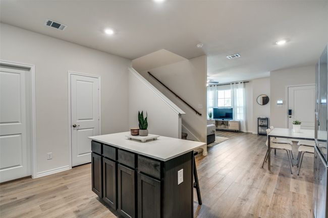 Kitchen featuring light wood-style flooring, a kitchen island, a breakfast bar area, light countertops, and recessed lighting | Image 11