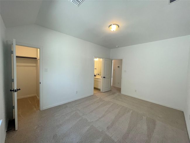 Unfurnished bedroom featuring a spacious closet, light carpet, lofted ceiling, connected bathroom, and a closet | Image 27