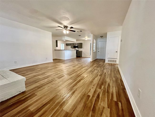 Unfurnished living room with ceiling fan, wood finished floors, and baseboards | Image 5