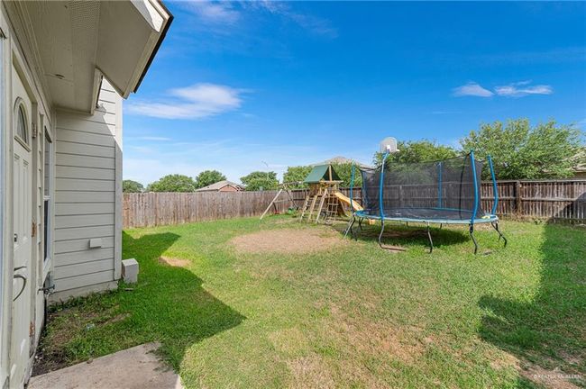 Fenced backyard featuring a trampoline and a playground | Image 34