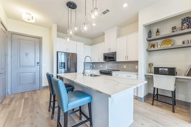 Kitchen with light wood finished floors, a breakfast bar area, white cabinets, and appliances with stainless steel finishes | Image 10