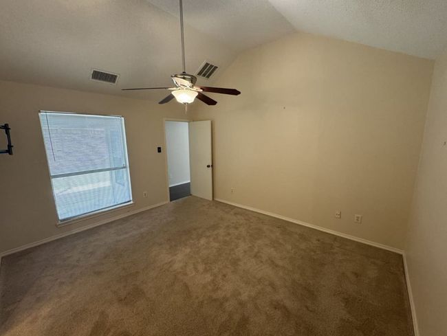 Master bedroom with ceiling fan, light tile floors, a textured ceiling, ensuite bath, and lofted ceiling | Image 13