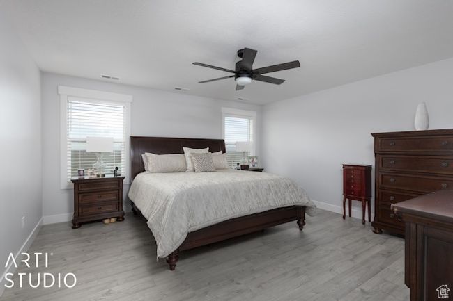 Bedroom with visible vents, baseboards, light wood-style floors, and a ceiling fan | Image 30