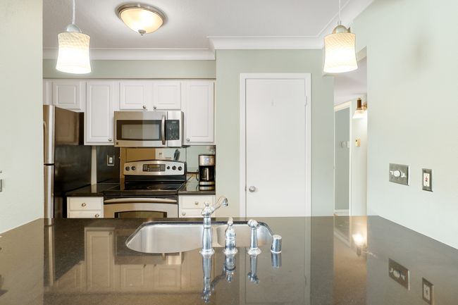 Kitchen with stainless steel appliances, ornamental molding, a sink, pendant lighting, and white cabinetry | Image 6