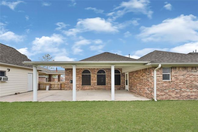 Spacious backyard patio with a covered patio. It features arched windows with solar screens. This space is perfect for outdoor activities and relaxation. | Image 27