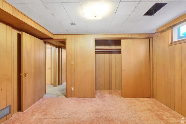 Unfurnished bedroom featuring carpet flooring, a closet, and wood walls | Image 28