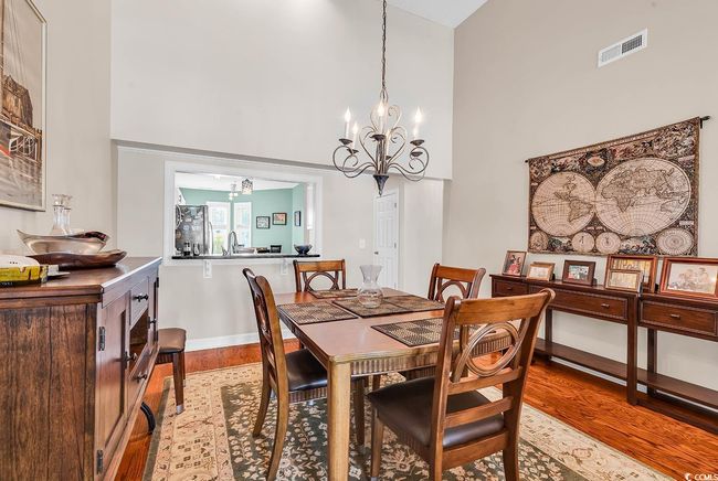 Dining room with wood finished floors, visible vents, baseboards, a chandelier, and high vaulted ceiling | Image 8
