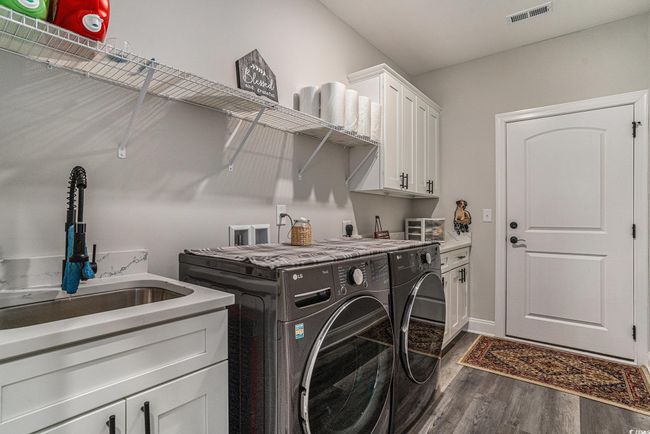 Clothes washing area with independent washer and dryer, dark wood-style floors, and cabinet space | Image 27