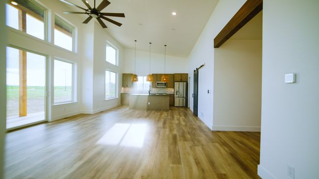 Unfurnished living room with a high ceiling, light wood finished floors, ceiling fan, a barn door, and recessed lighting | Image 25