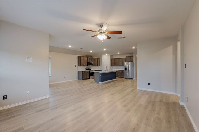Unfurnished living room featuring a sink, ceiling fan, light wood-type flooring, visible vents, and baseboards | Image 9