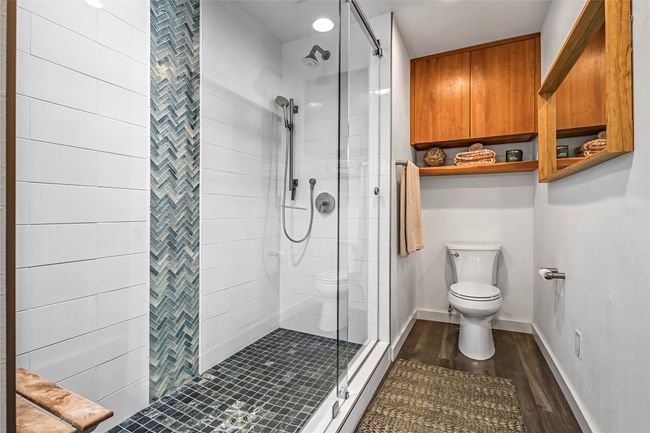 Full bath featuring toilet, a stall shower, wood finished floors, and baseboards | Image 25