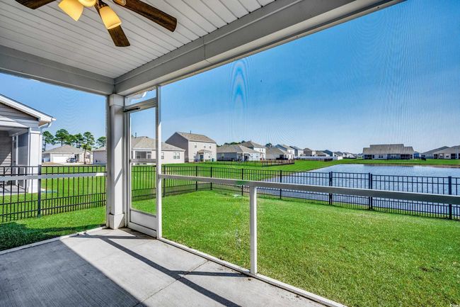 Unfurnished sunroom featuring a water view, a residential view, and a ceiling fan | Image 10